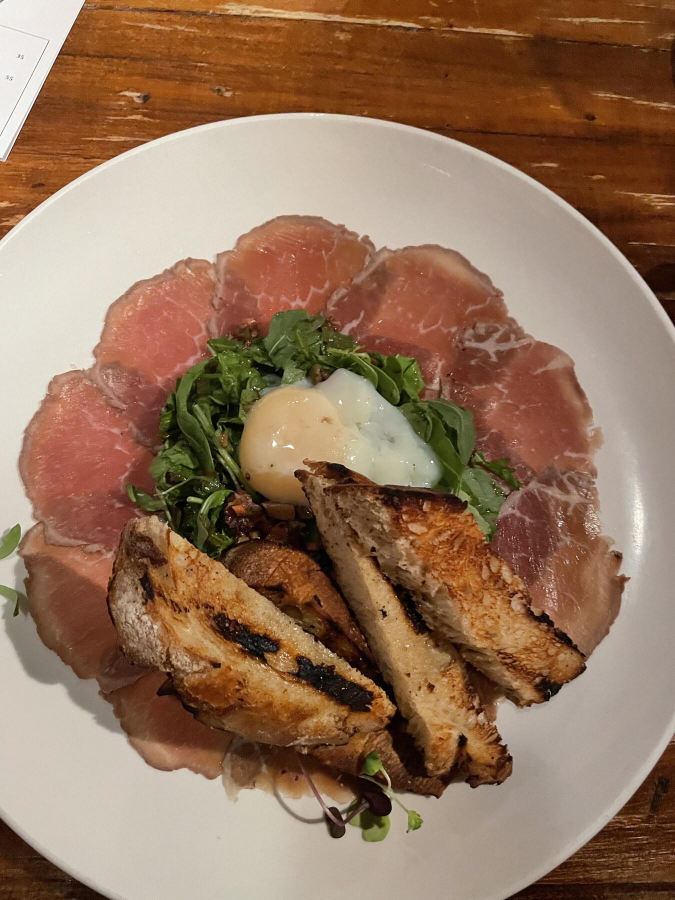 Carpaccio-style plate with roasted mushrooms and fresh herbs